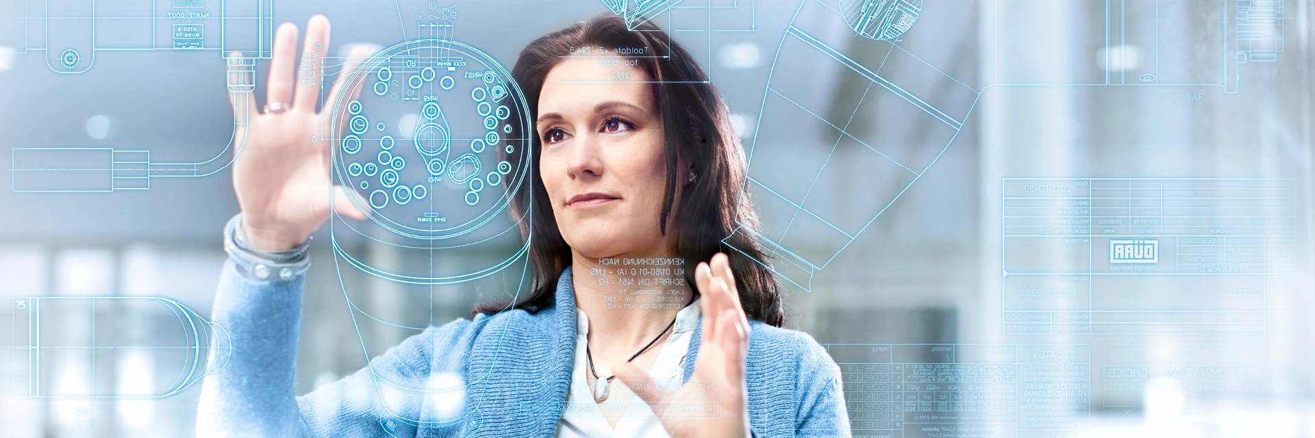 Woman interacting with a transparent touchscreen displaying technical engineering schematics and digital interface elements.