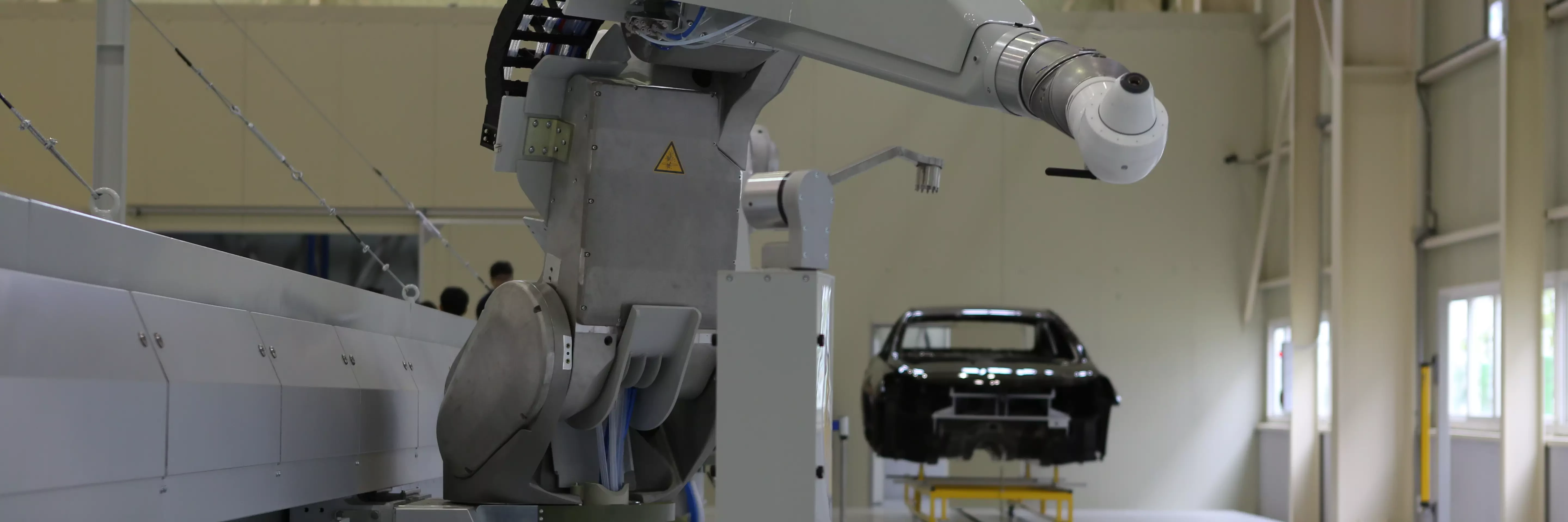 Industrieroboterarm in einer Trainingsanlage in Korea, positioniert neben einer Karosserie auf einem Gestell.